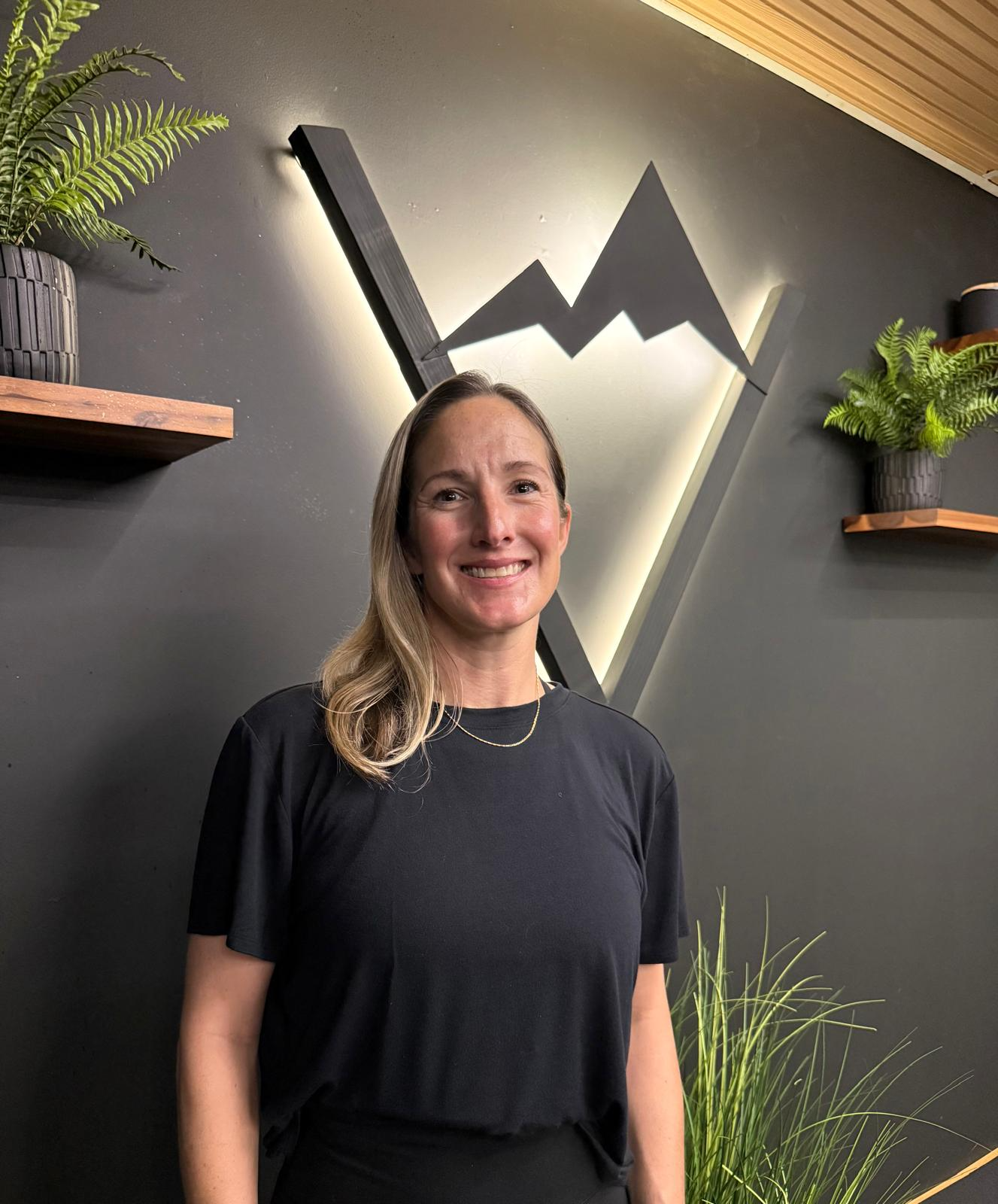 Katy smiling in front of the illuminated Valley Studio mountain logo