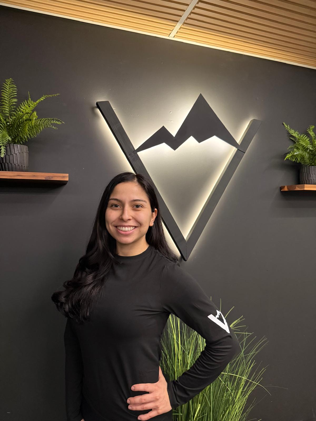 Gloria smiling in front of the illuminated Valley Studio mountain logo